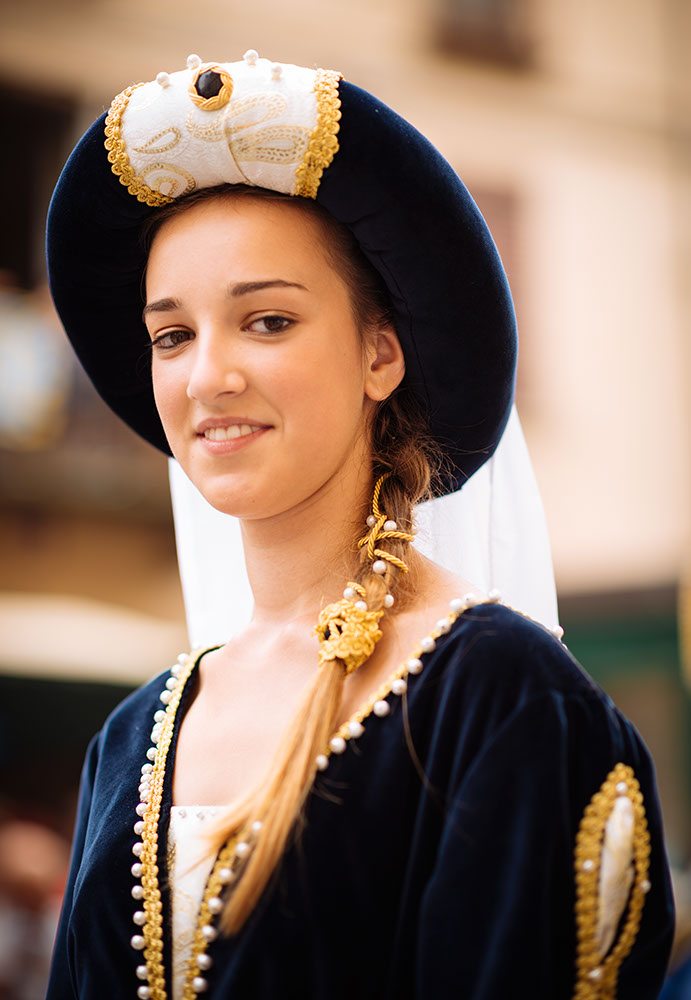 A girl in a medieval costume takes part in a historical parade from the Piazza Cattedrale to the race track ahead of the Palio Di Asti on September 21, 2014 in Asti, Italy